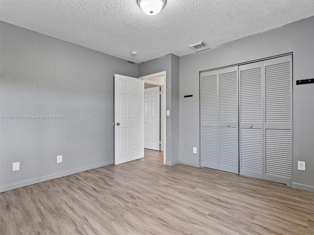 unfurnished bedroom with a closet, a textured ceiling, and light hardwood / wood-style floors