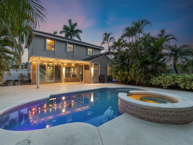 pool at dusk with a patio, a pergola, and an in ground hot tub