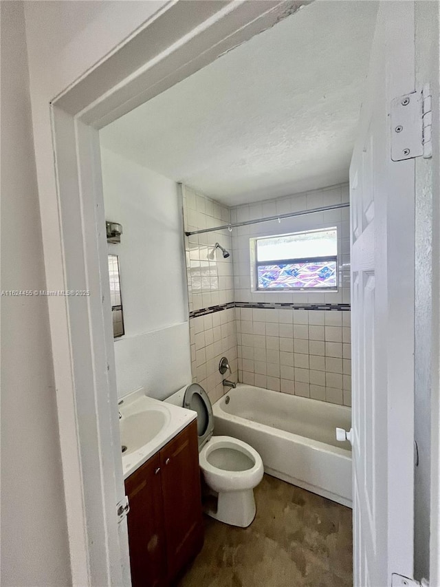 full bathroom featuring tiled shower / bath, vanity, and toilet