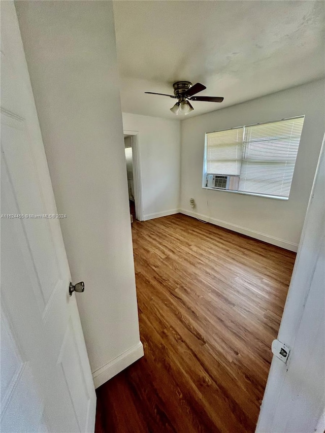 spare room with hardwood / wood-style flooring, cooling unit, and ceiling fan