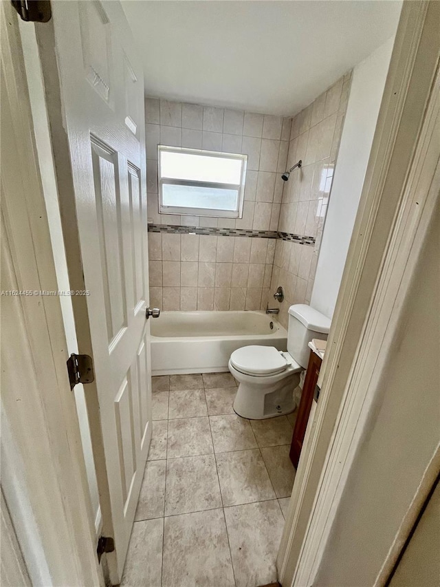 bathroom with tiled shower / bath combo, tile patterned floors, and toilet