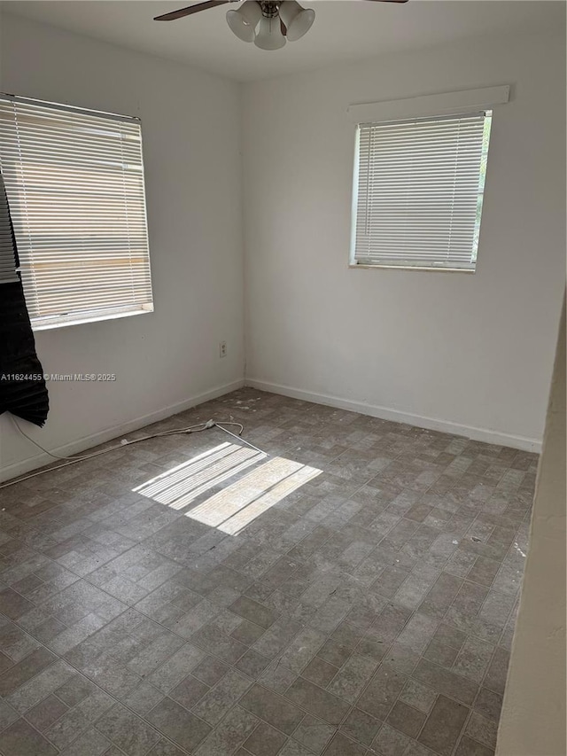 empty room with ceiling fan and a wealth of natural light