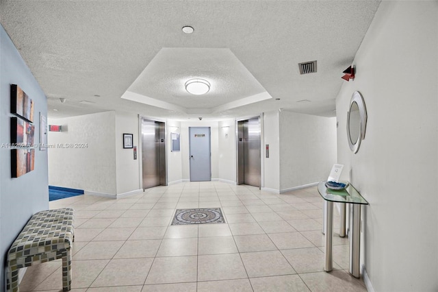 1000 Saint Charles Pl Unit 522, Pembroke Pines, FL 33026 - hall featuring elevator, a textured ceiling, a raised ceiling, light tile patterned floors, and baseboards