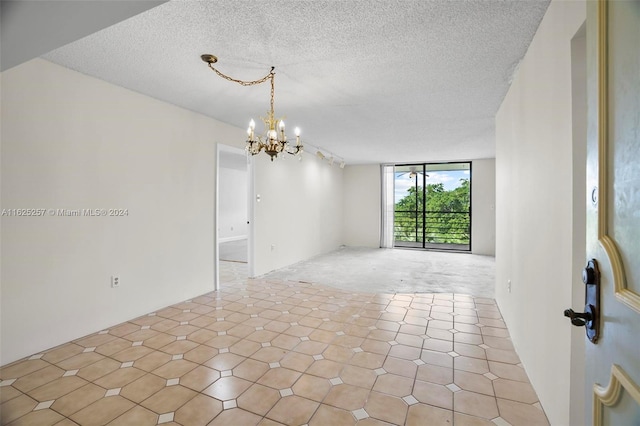 empty room with a chandelier and a textured ceiling