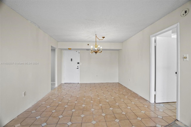 unfurnished room with light tile patterned floors, a textured ceiling, and a chandelier