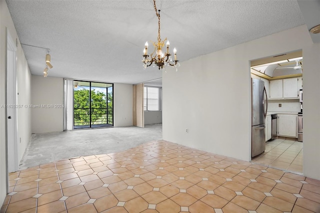 spare room with a notable chandelier and a textured ceiling