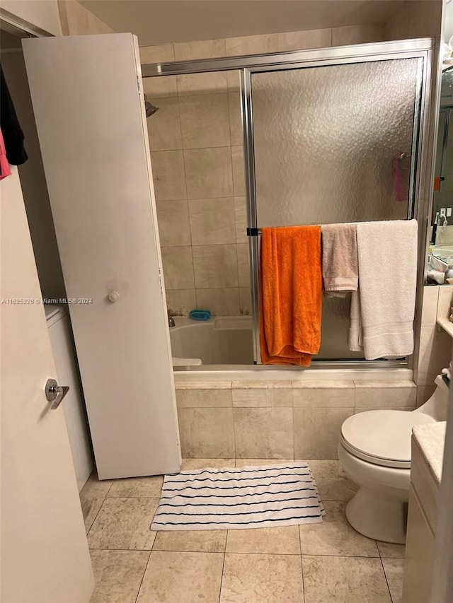 full bathroom featuring tile patterned flooring, bath / shower combo with glass door, toilet, and vanity