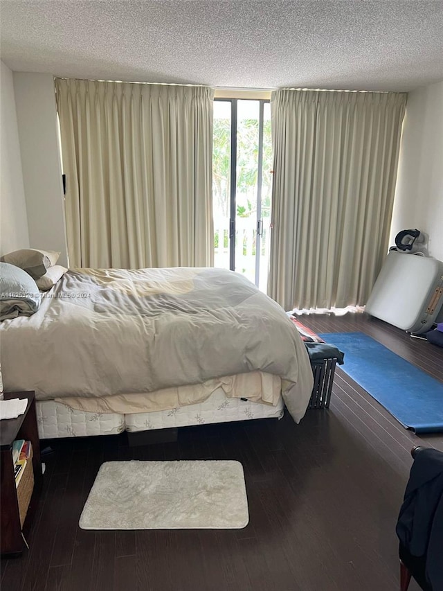 bedroom with hardwood / wood-style flooring, access to outside, and a textured ceiling