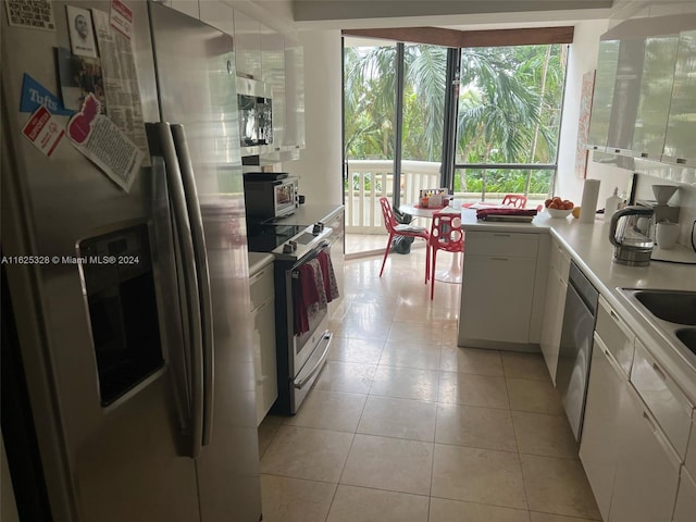 kitchen featuring light tile patterned flooring, white cabinetry, appliances with stainless steel finishes, and plenty of natural light