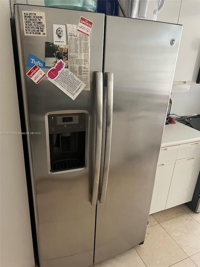 interior space featuring white cabinets, stainless steel fridge, and light tile patterned floors