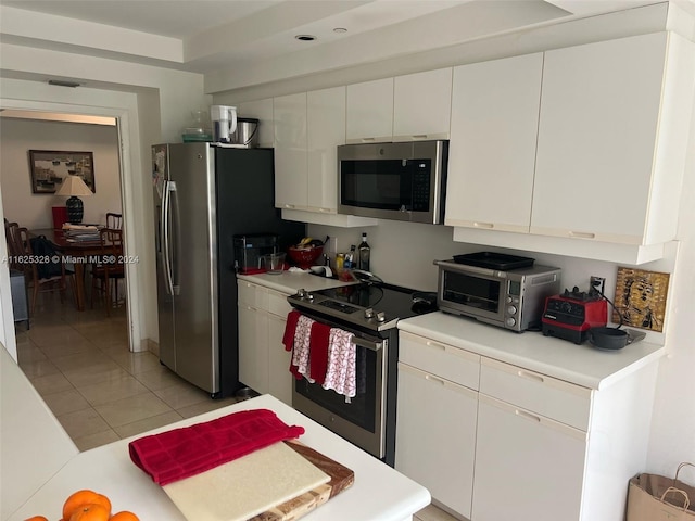 kitchen with appliances with stainless steel finishes, white cabinets, and light tile patterned floors