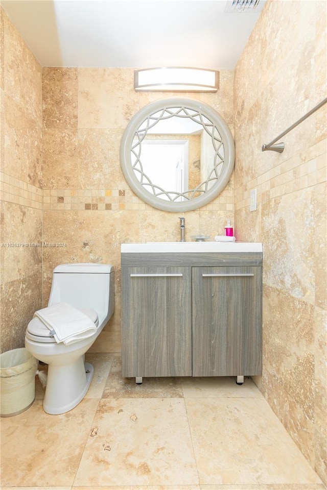 bathroom with toilet, tile patterned flooring, and tile walls