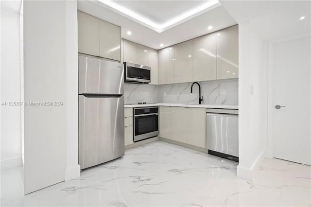 kitchen with light tile patterned floors, stainless steel appliances, decorative backsplash, sink, and gray cabinetry