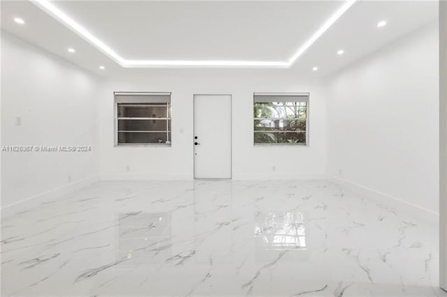 tiled spare room featuring a raised ceiling