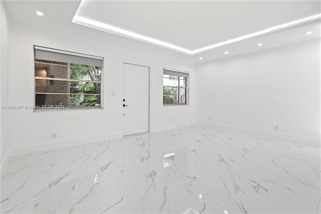 spare room with tile patterned flooring and a tray ceiling