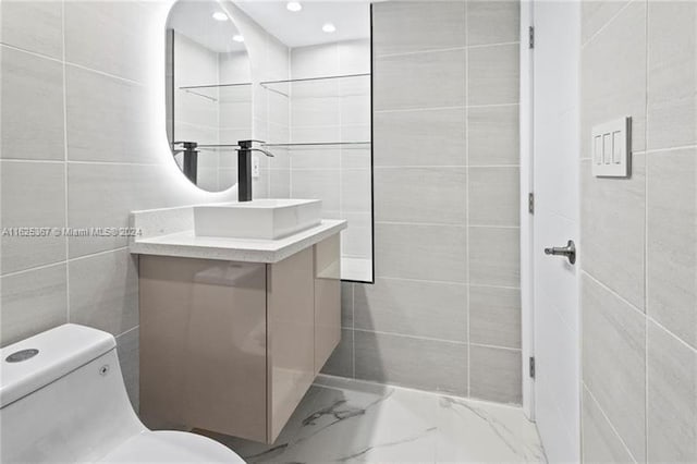 bathroom with vanity, tile walls, and toilet