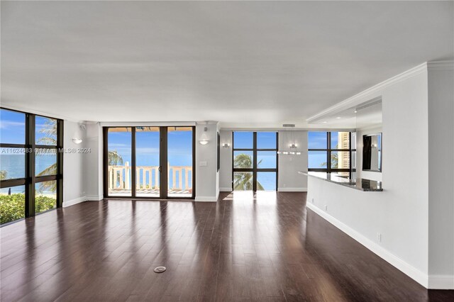 unfurnished living room featuring a wall of windows, a healthy amount of sunlight, a water view, and dark hardwood / wood-style flooring