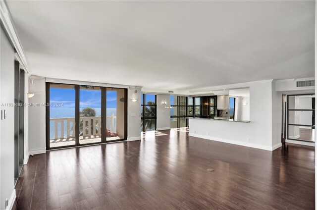 unfurnished living room with expansive windows, a water view, and dark hardwood / wood-style floors