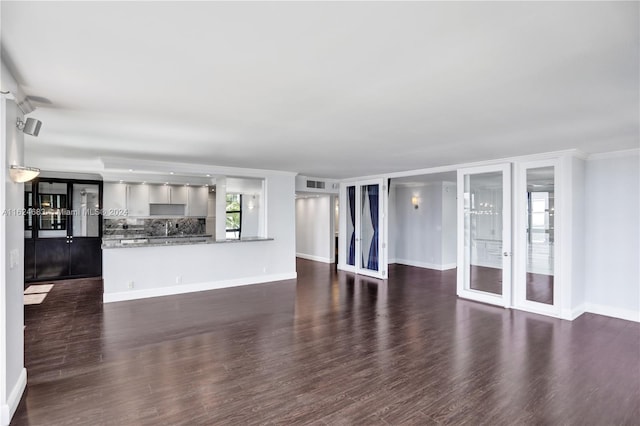 unfurnished living room with dark wood-type flooring and french doors