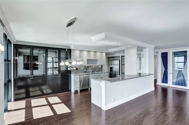 kitchen with hanging light fixtures, dark hardwood / wood-style flooring, decorative backsplash, light stone countertops, and appliances with stainless steel finishes