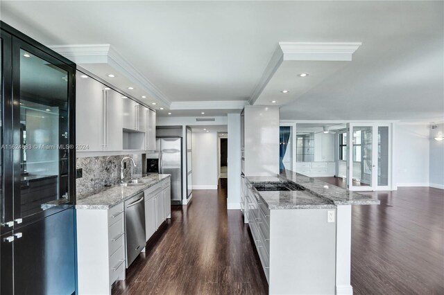 kitchen featuring dark hardwood / wood-style flooring, decorative backsplash, white cabinets, light stone countertops, and appliances with stainless steel finishes