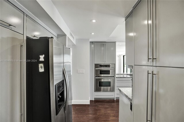 kitchen with dark wood-type flooring, light stone countertops, stainless steel appliances, and gray cabinets