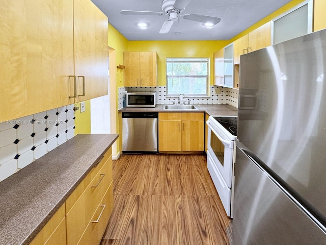 kitchen with stainless steel appliances, light brown cabinets, a sink, and backsplash