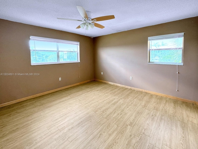 unfurnished room featuring baseboards, ceiling fan, a textured ceiling, and light wood finished floors