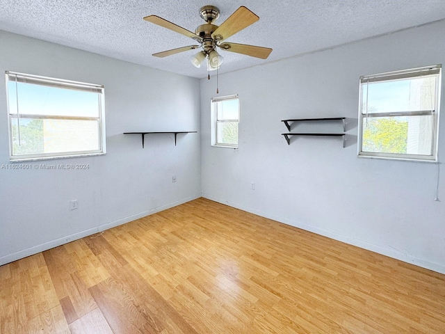 spare room with light wood-type flooring, ceiling fan, baseboards, and a textured ceiling