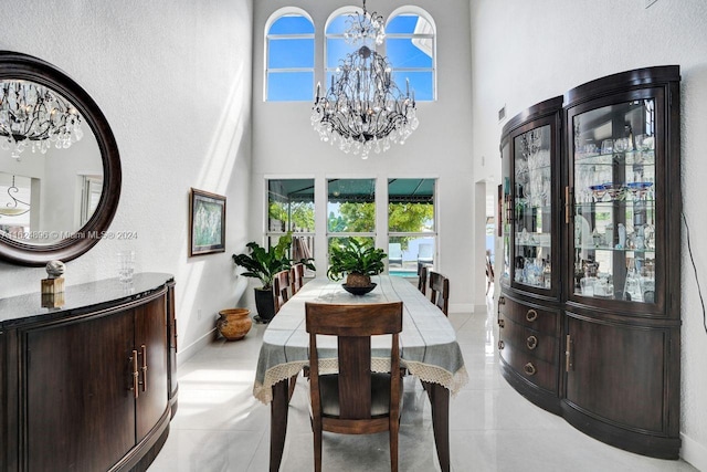 dining space with a high ceiling, light tile patterned floors, and an inviting chandelier