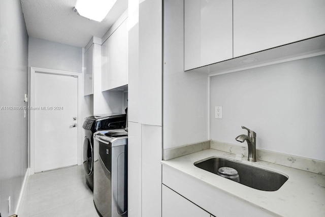 interior space featuring light tile patterned flooring, a textured ceiling, independent washer and dryer, cabinets, and sink