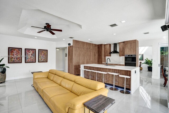 living room with light tile patterned floors, sink, and ceiling fan