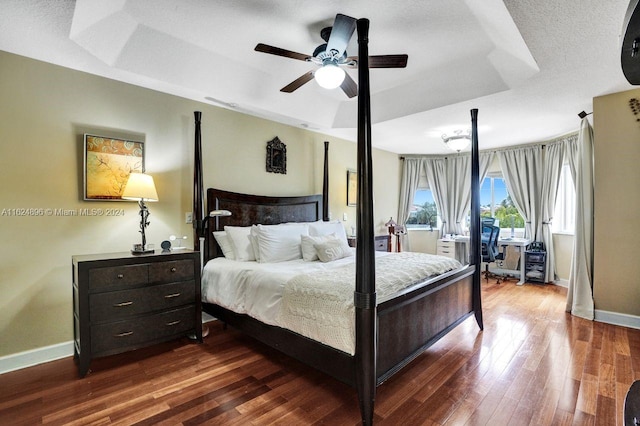 bedroom featuring ceiling fan, hardwood / wood-style flooring, and a raised ceiling