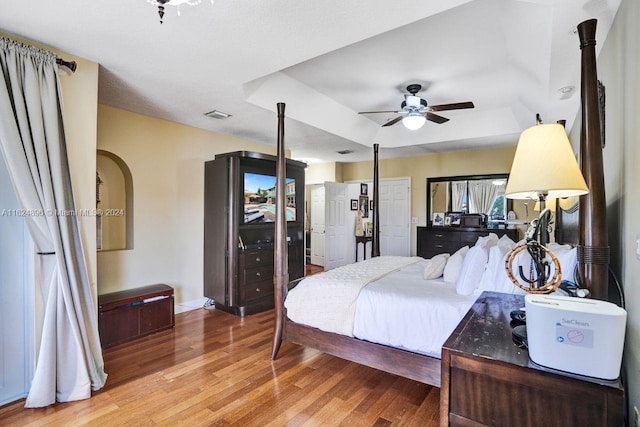 bedroom with a tray ceiling, light hardwood / wood-style flooring, and ceiling fan