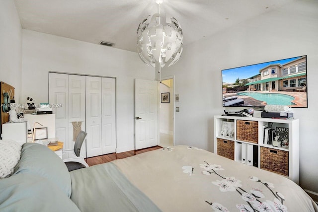 bedroom with wood-type flooring, a notable chandelier, and a closet