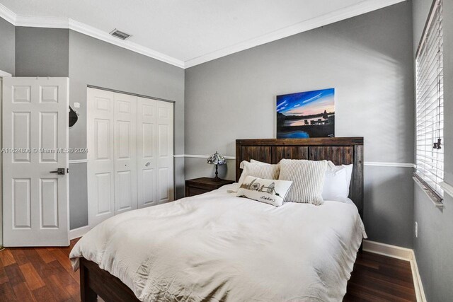 bedroom with dark hardwood / wood-style flooring, a closet, and crown molding