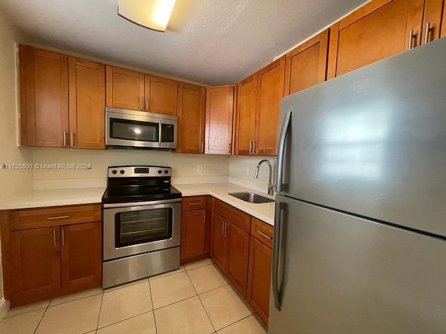 kitchen with sink, light tile patterned floors, a textured ceiling, and appliances with stainless steel finishes