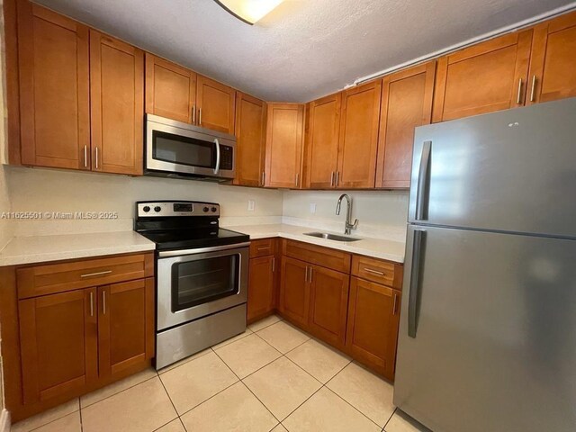 kitchen with appliances with stainless steel finishes, light tile patterned flooring, and sink