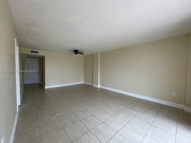 spare room featuring floor to ceiling windows, light tile patterned floors, and ceiling fan