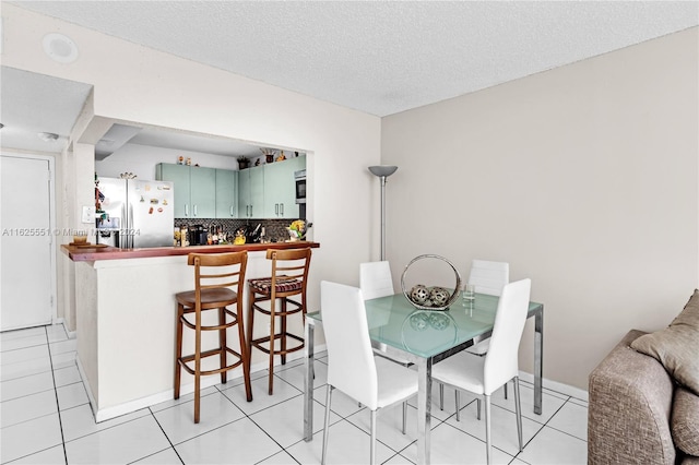 dining space with bar, a textured ceiling, and light tile patterned floors