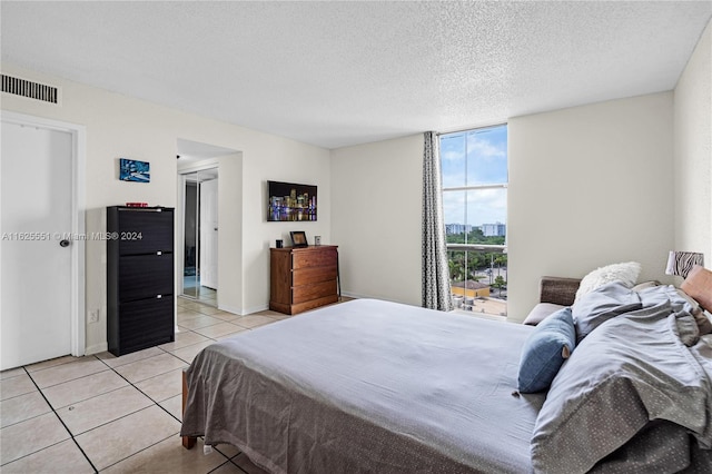 bedroom featuring a textured ceiling, a wall of windows, and light tile patterned floors