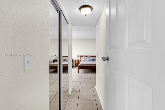 hall with light tile patterned flooring and a textured ceiling