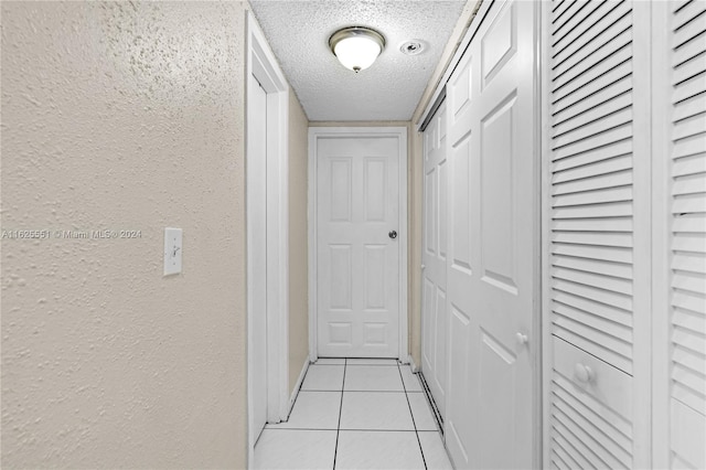 corridor with light tile patterned floors and a textured ceiling