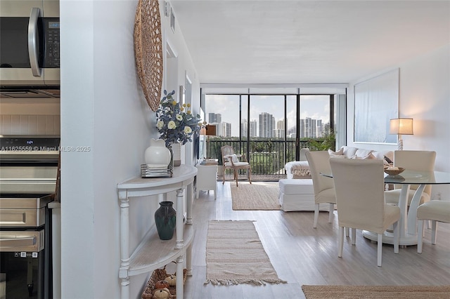 living room with a wall of windows and light hardwood / wood-style flooring