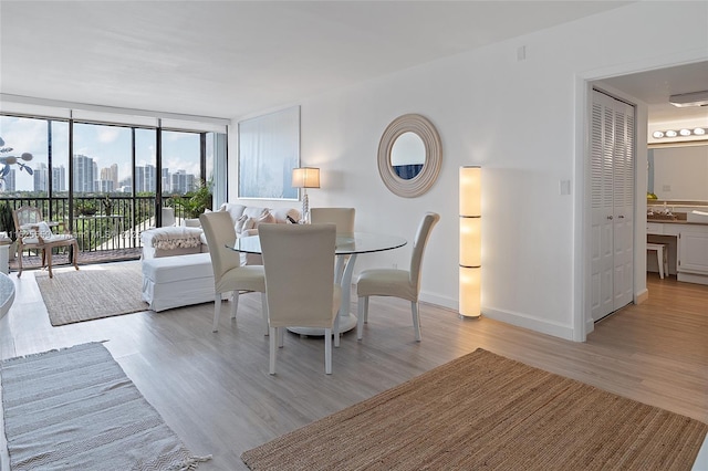 dining space with a wall of windows and light wood-type flooring