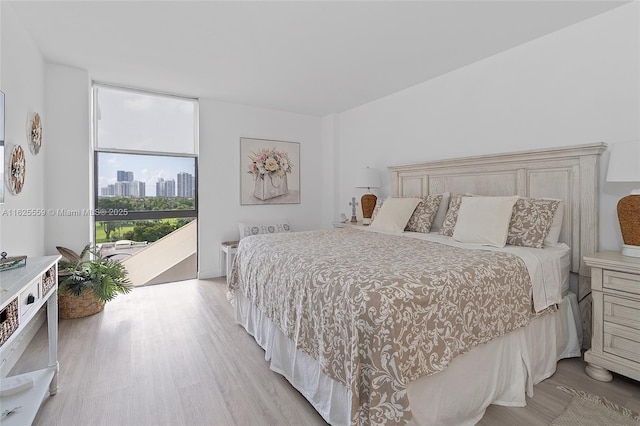 bedroom with access to exterior, expansive windows, and light wood-type flooring