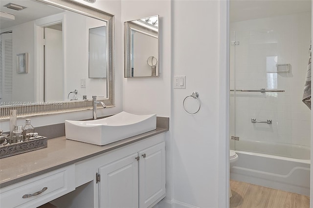 full bathroom with hardwood / wood-style flooring, vanity, tiled shower / bath combo, and toilet