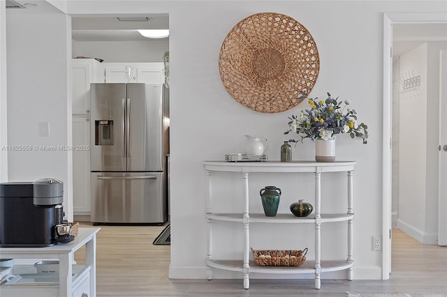 interior space with stainless steel refrigerator with ice dispenser and light hardwood / wood-style flooring