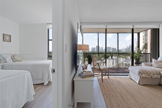 bedroom featuring floor to ceiling windows, light wood-type flooring, and access to outside