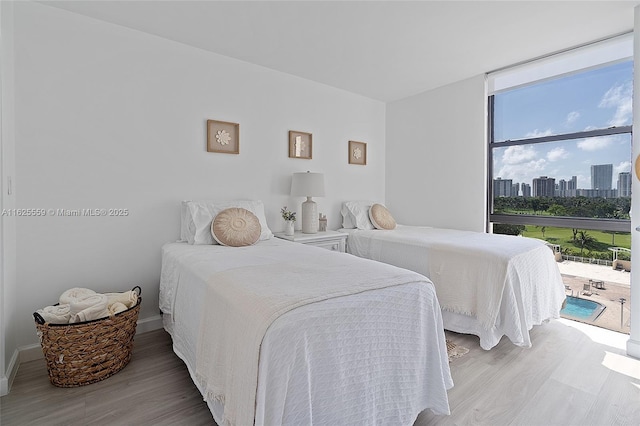 bedroom with floor to ceiling windows, light hardwood / wood-style floors, and access to outside